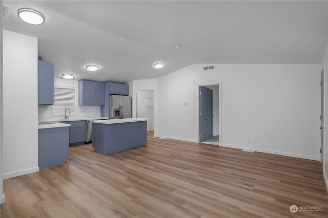 kitchen featuring lofted ceiling, sink, stainless steel appliances, light hardwood / wood-style floors, and a kitchen island