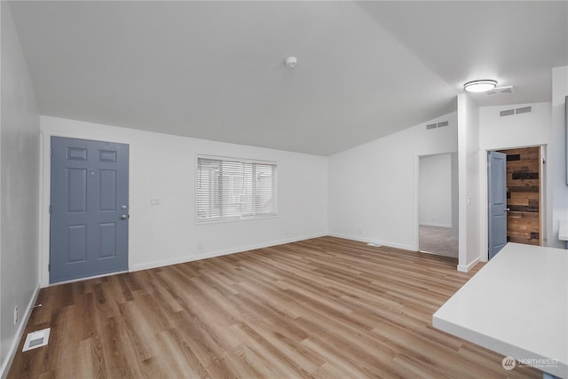 unfurnished living room featuring lofted ceiling and light hardwood / wood-style floors