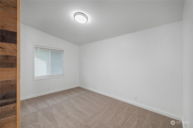 unfurnished room featuring light carpet and vaulted ceiling