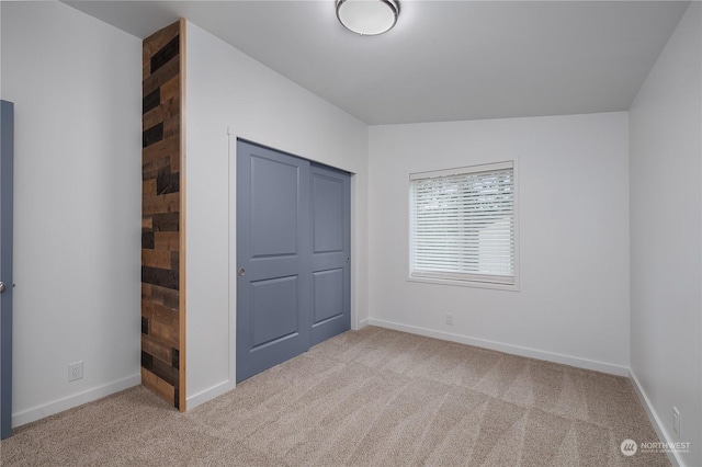 unfurnished bedroom featuring lofted ceiling, light colored carpet, and a closet