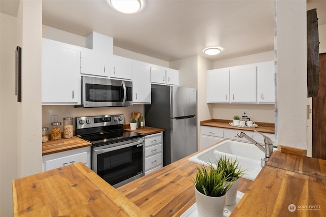 kitchen featuring white cabinets, sink, stainless steel appliances, and wooden counters