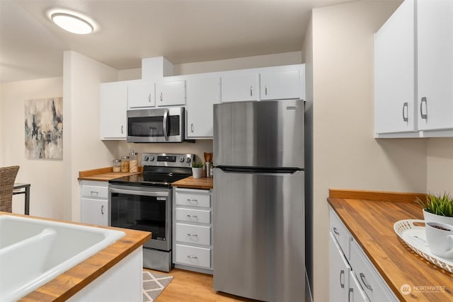 kitchen with wood counters, stainless steel appliances, and white cabinetry