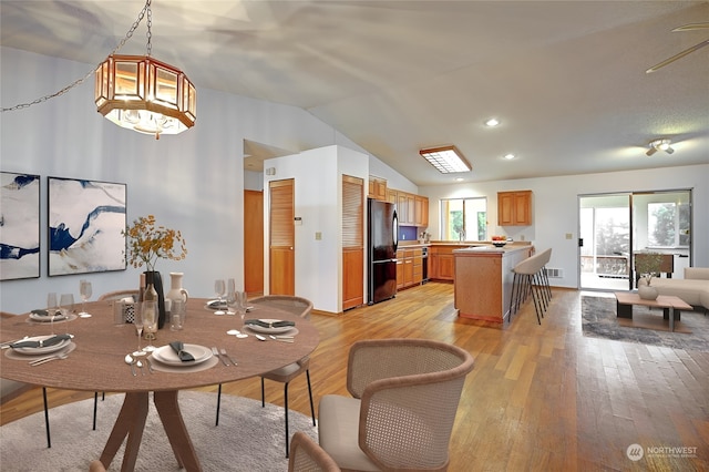 dining area featuring lofted ceiling, light wood-type flooring, and a wealth of natural light