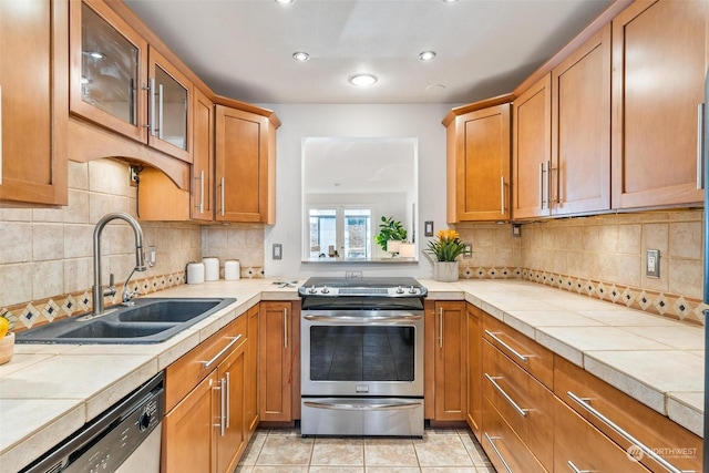 kitchen with sink, tile counters, decorative backsplash, and stainless steel appliances