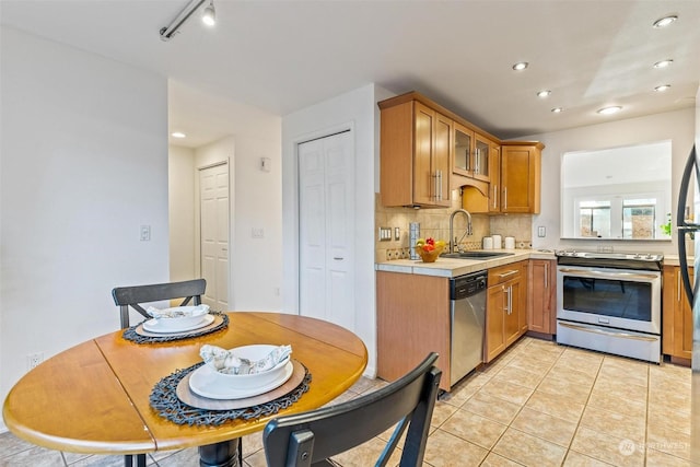 kitchen with sink, backsplash, light tile patterned floors, track lighting, and stainless steel appliances