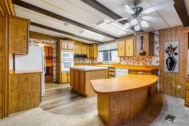 kitchen featuring a center island, white appliances, sink, vaulted ceiling with beams, and ceiling fan