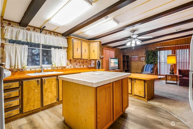 kitchen featuring tile countertops, sink, beamed ceiling, and a kitchen island