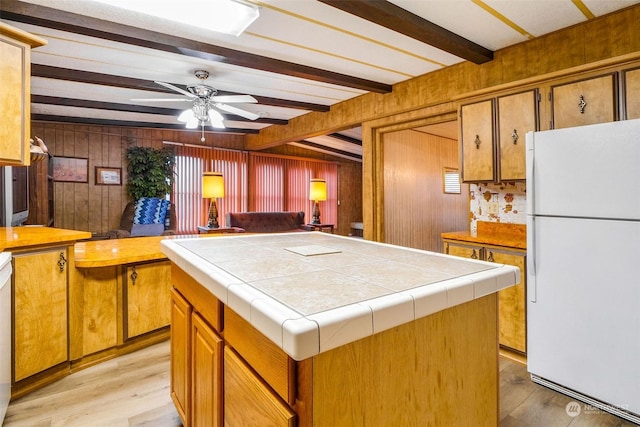 kitchen featuring tile countertops, a center island, beamed ceiling, and white refrigerator