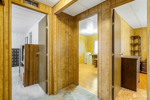 hallway with light colored carpet and wooden walls