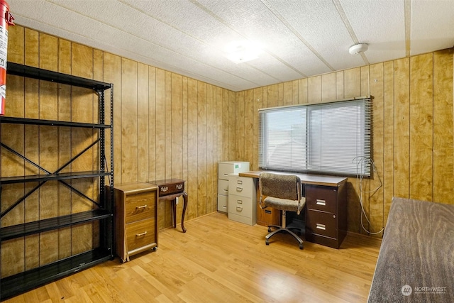 office with wooden walls and light hardwood / wood-style flooring