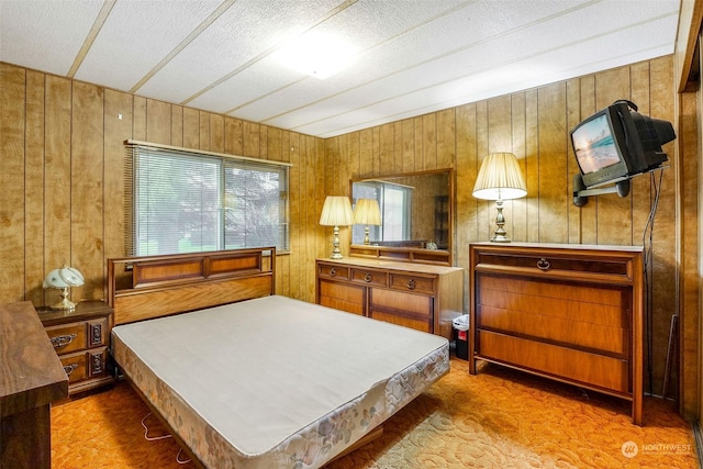 carpeted bedroom featuring wooden walls