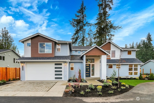 view of front of house featuring a shingled roof, fence, driveway, and an attached garage