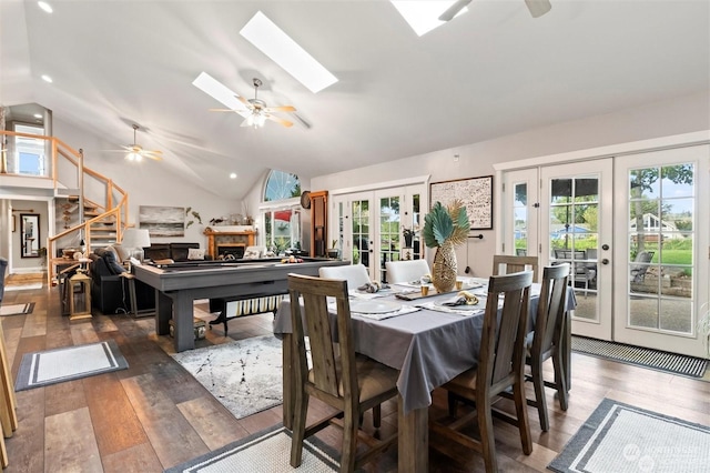 dining room with dark hardwood / wood-style flooring, ceiling fan, french doors, and vaulted ceiling with skylight