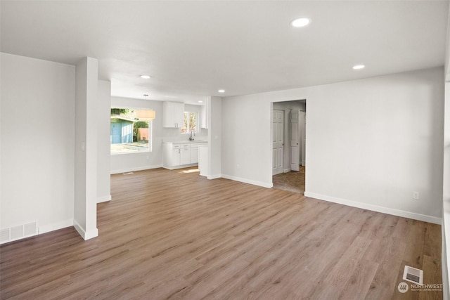 unfurnished living room featuring sink and light wood-type flooring