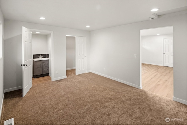 unfurnished bedroom with ensuite bath and light colored carpet