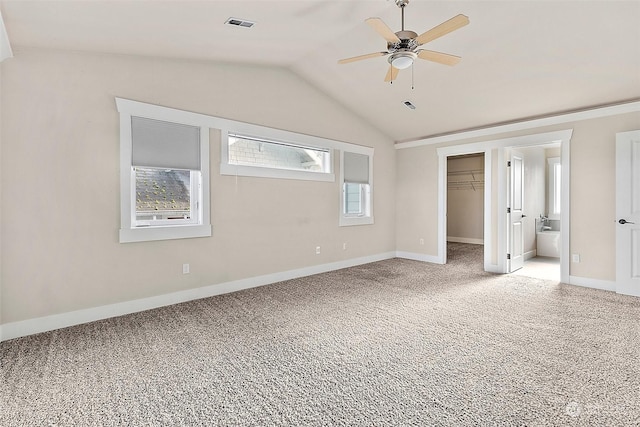 unfurnished bedroom with carpet flooring, a walk in closet, vaulted ceiling, ceiling fan, and a closet