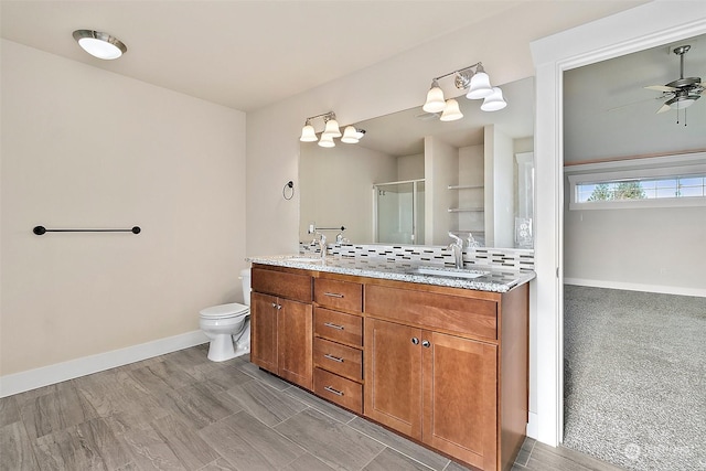 bathroom with ceiling fan, backsplash, toilet, vanity, and a shower with shower door