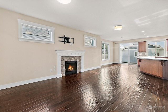 unfurnished living room featuring a stone fireplace and dark wood-type flooring