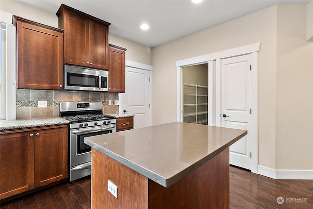 kitchen featuring dark wood-type flooring, light stone countertops, tasteful backsplash, a kitchen island, and stainless steel appliances