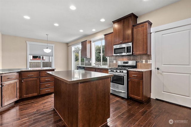 kitchen with dark hardwood / wood-style floors, a center island, hanging light fixtures, and appliances with stainless steel finishes