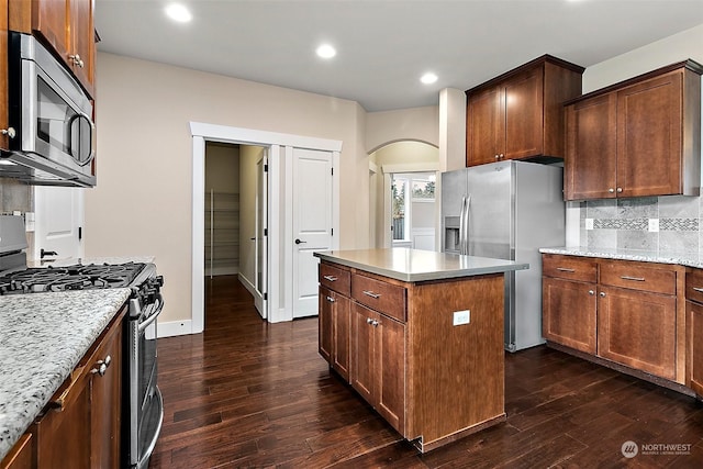 kitchen with backsplash, a center island, dark hardwood / wood-style floors, and appliances with stainless steel finishes