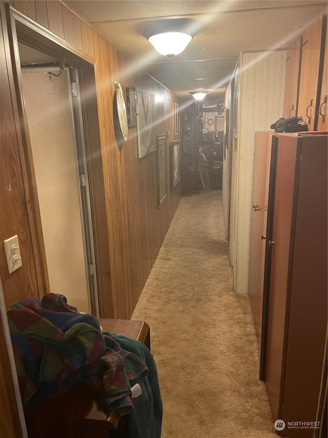 hall with wood walls and light colored carpet