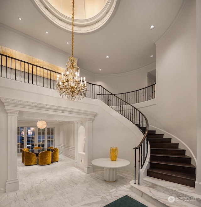 staircase with a chandelier, french doors, ornamental molding, and a high ceiling