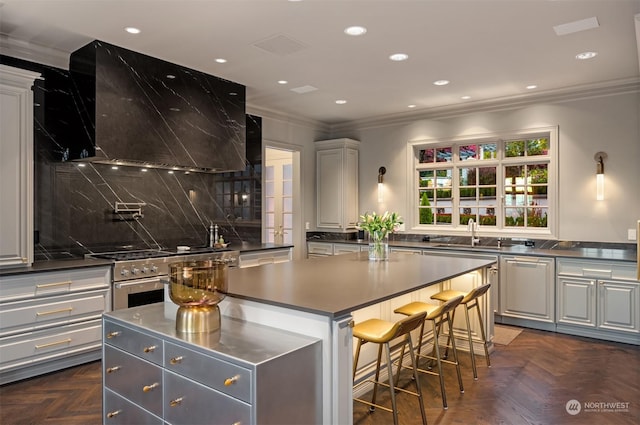 kitchen featuring dark parquet flooring, wall chimney range hood, high end stainless steel range, a kitchen island, and a breakfast bar area