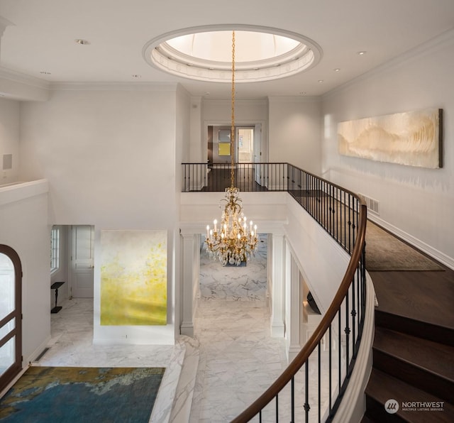 stairway with a tray ceiling, an inviting chandelier, and ornamental molding