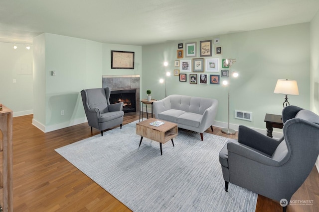 living room featuring a tiled fireplace and hardwood / wood-style floors