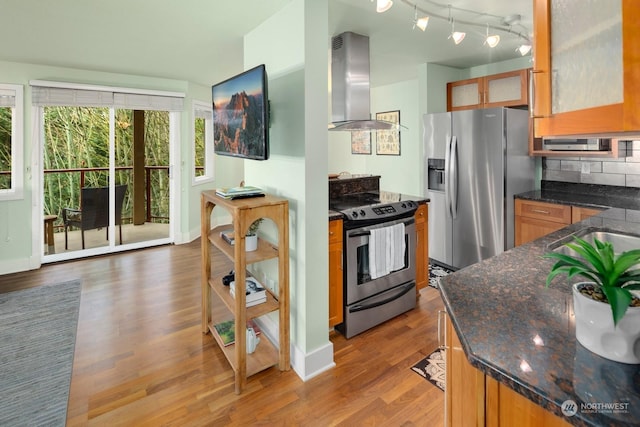 kitchen featuring backsplash, appliances with stainless steel finishes, island range hood, and light wood-type flooring