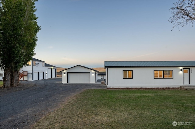 view of front of house featuring an outdoor structure, a garage, and a yard