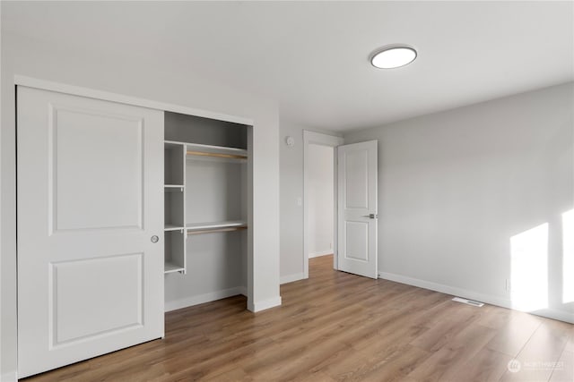 unfurnished bedroom with a closet and light hardwood / wood-style floors