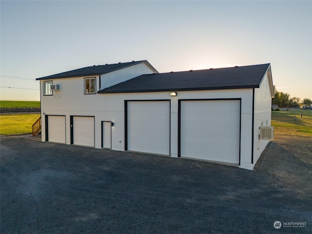 garage at dusk featuring an AC wall unit