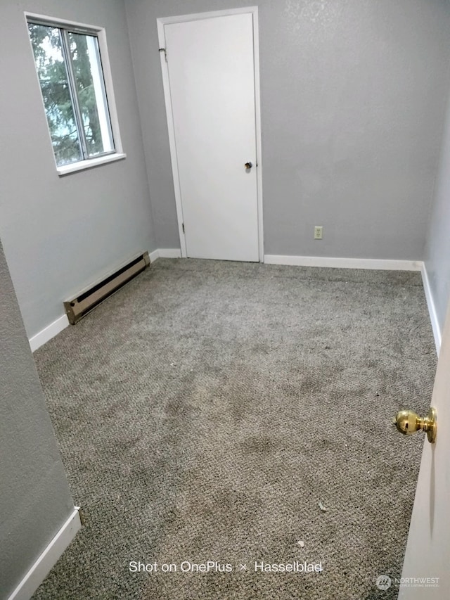 spare room featuring baseboard heating and carpet floors