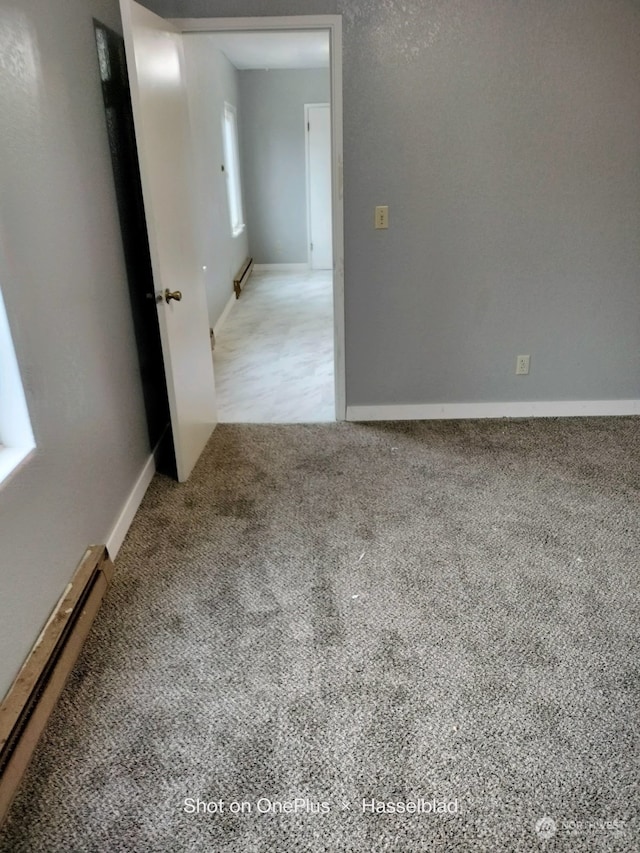 carpeted empty room with baseboard heating