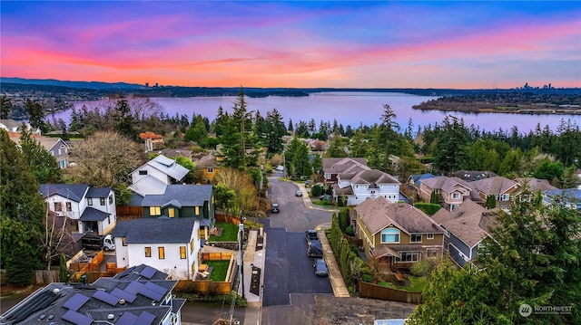 aerial view at dusk featuring a water view