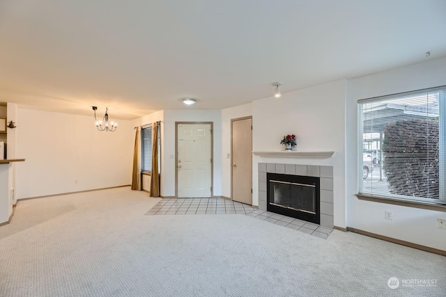 unfurnished living room featuring a fireplace, a chandelier, and light carpet