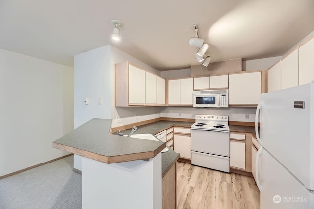 kitchen featuring rail lighting, sink, kitchen peninsula, white appliances, and light hardwood / wood-style floors