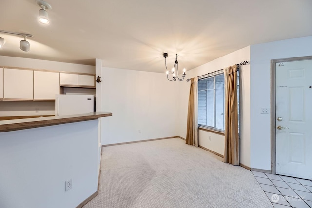 kitchen with decorative light fixtures, white cabinetry, a chandelier, white fridge, and light colored carpet