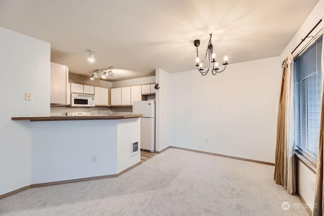 kitchen with decorative light fixtures, white cabinets, light colored carpet, kitchen peninsula, and white appliances