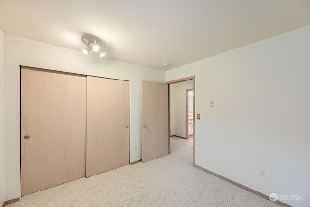 unfurnished bedroom with light carpet and a closet