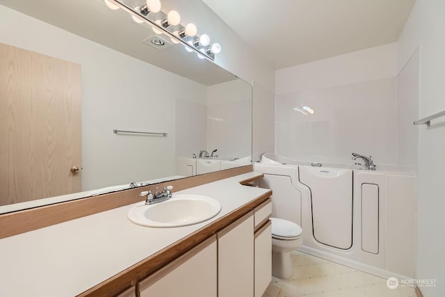 bathroom with a washtub, vanity, and toilet