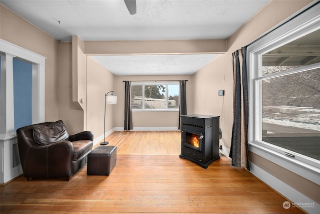 living room featuring ceiling fan, light hardwood / wood-style flooring, and a textured ceiling