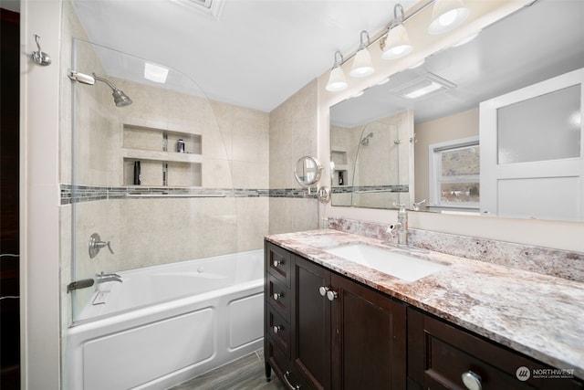 bathroom with hardwood / wood-style floors, vanity, and tiled shower / bath