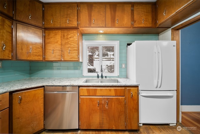 kitchen featuring sink, stainless steel dishwasher, light hardwood / wood-style floors, tasteful backsplash, and white fridge