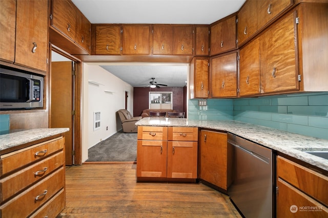 kitchen featuring decorative backsplash, ceiling fan, wood-type flooring, and appliances with stainless steel finishes