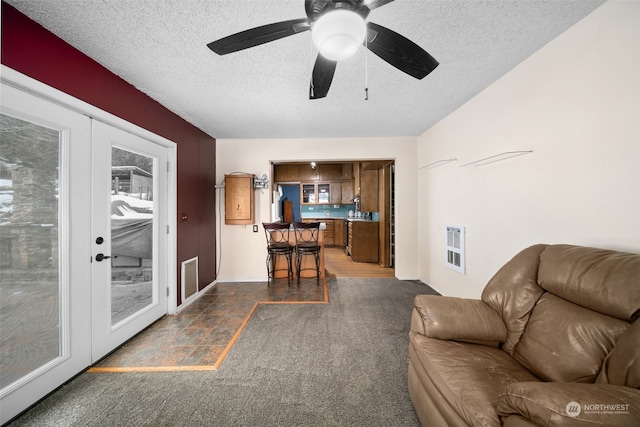 living room with ceiling fan, french doors, and a textured ceiling