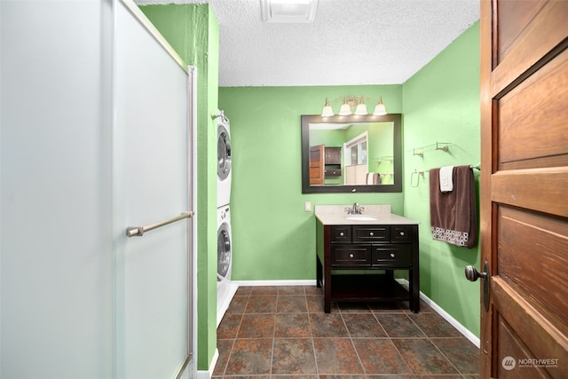 bathroom with vanity, stacked washing maching and dryer, and a textured ceiling