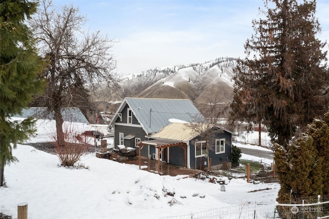 snow covered back of property with a pergola